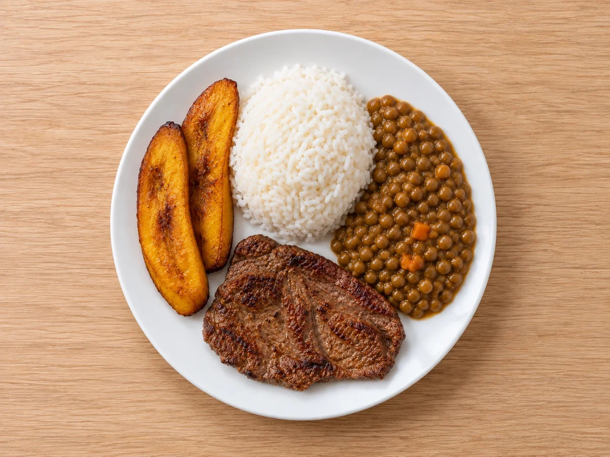 Menestra de lenteja con arroz blanco, carne de res asada y dos porciones de plátano maduro